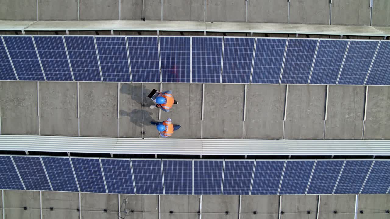 下面是两名员工在屋顶发电厂的光伏板之间行走视频素材