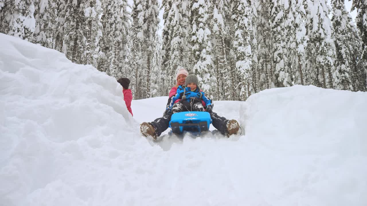 妈妈和儿子从雪山上滑下来视频素材
