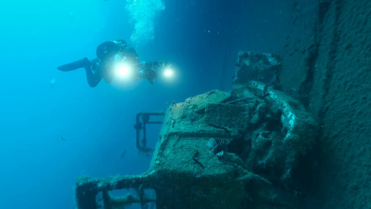 戴水肺的潜水员在沉船的瑞典渡轮MS Zenobia上拍摄客舱卡车。慢镜头，沉船潜水。地中海、塞浦路斯视频下载