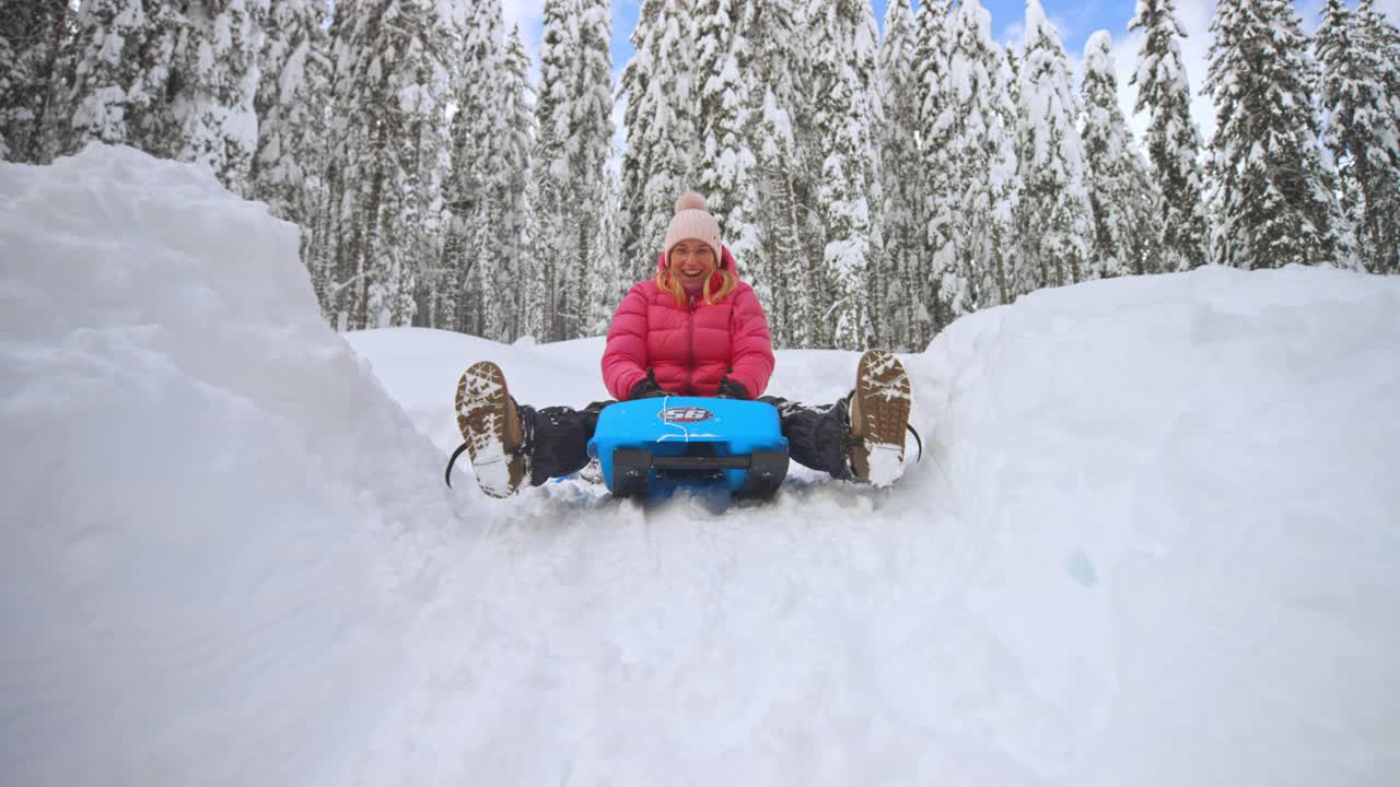 一个女人笑着从雪山上滑下来视频素材