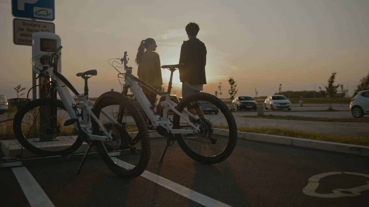 一对陌生的夫妇在电动汽车充电站为他们的电动自行车充电视频素材
