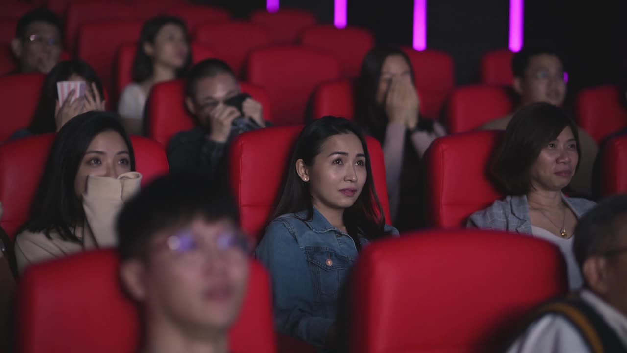 亚洲的中国人群在电影院看恐怖的惊悚电影视频下载