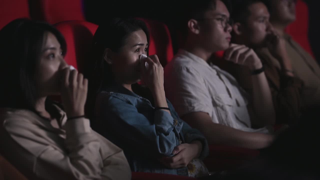 亚洲的中国女人在电影院看感伤的电影，在电影院用纸巾擦眼泪视频下载
