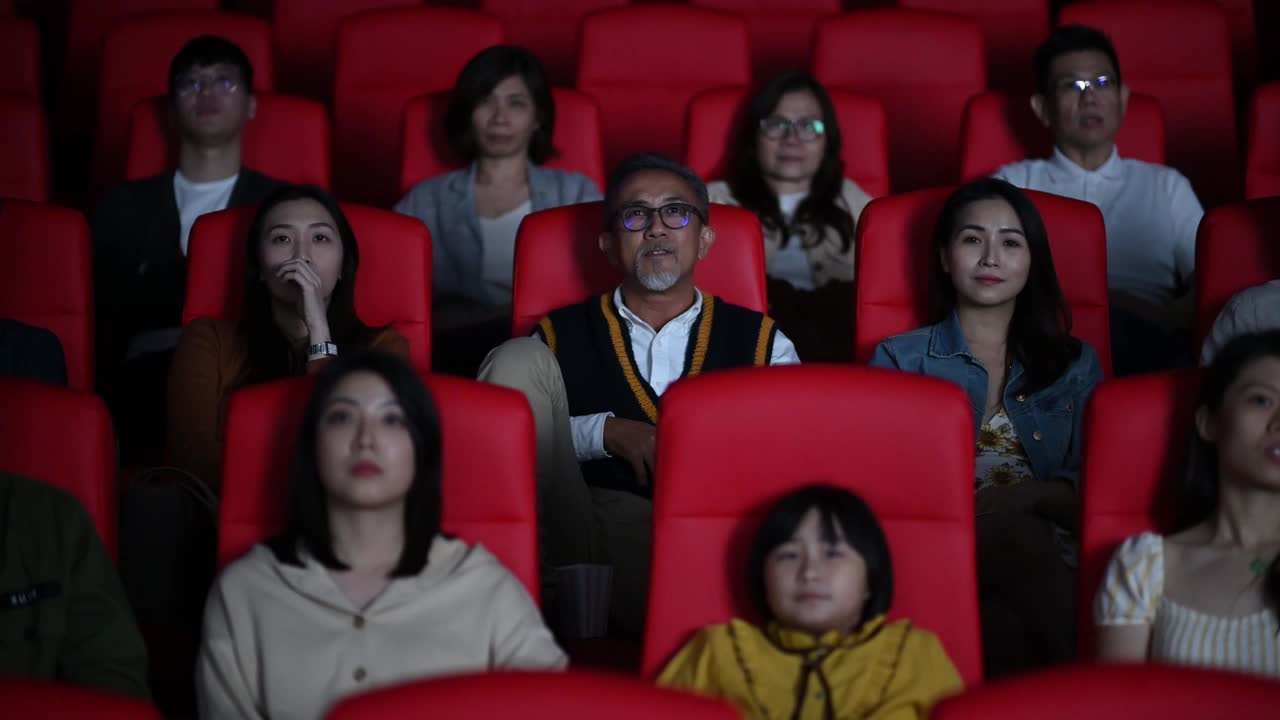 坏习惯:粗鲁的亚洲中国老人在电影放映期间大声讲电话，在黑暗中打扰和忽视他周围的其他观众。一个女孩把手指放在嘴唇上，轻拍他的肩膀，让他保持安静视频下载