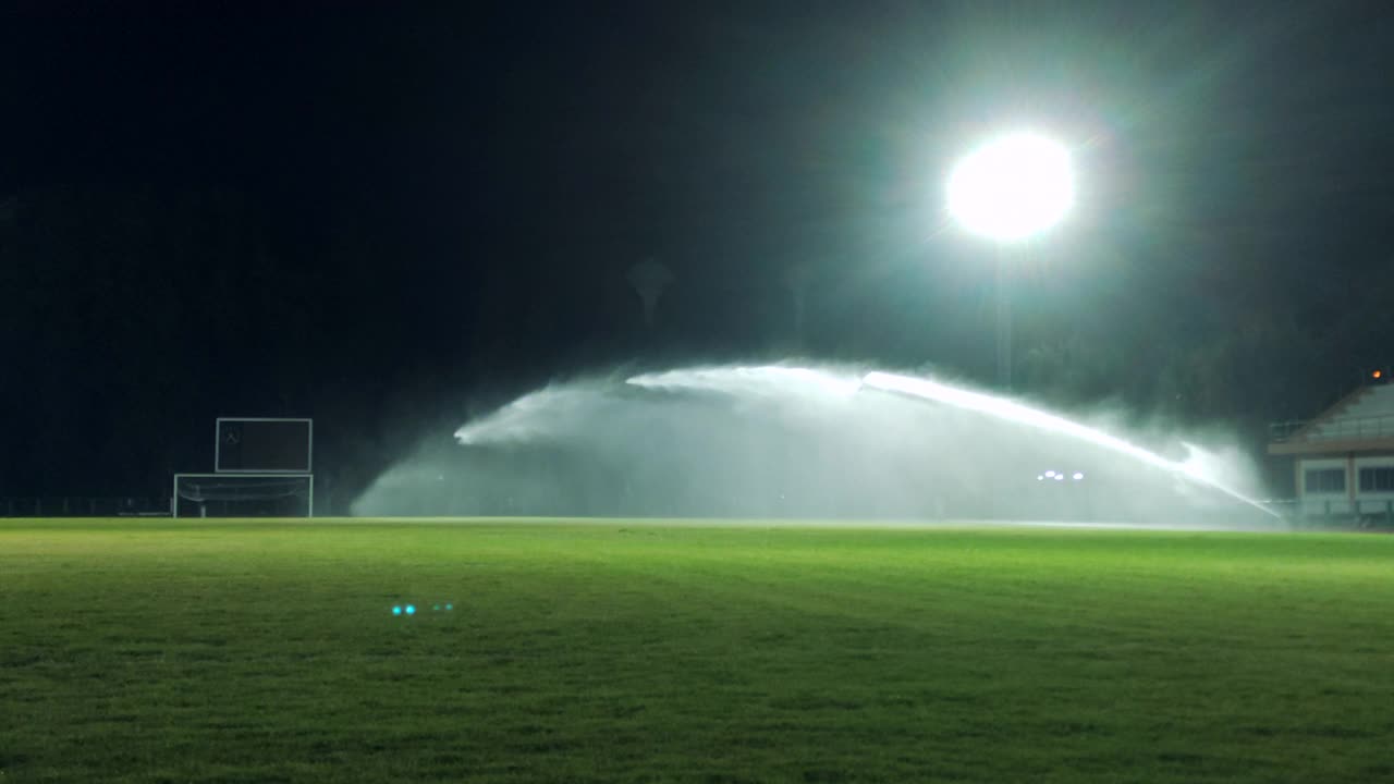 用智能手机慢动作拍摄夜间足球场上的洒水装置视频下载