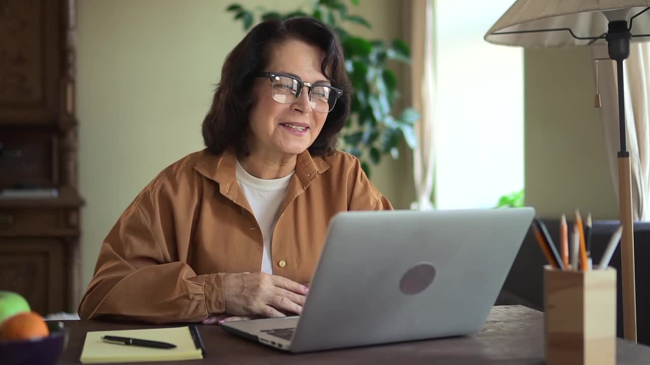 女人在线聊天，坐在桌子上与笔记本电脑在家庭房间视频素材