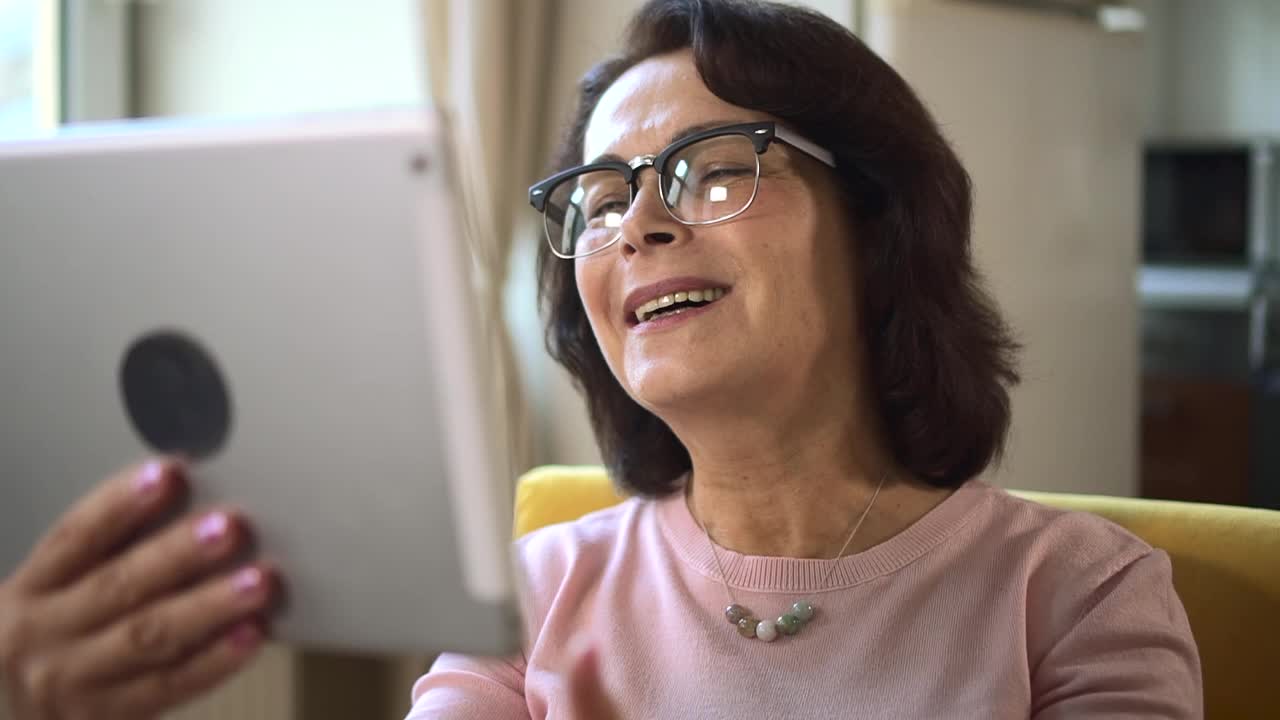 老妇人在平板电脑上结束视频通话，挥手并飞吻。祖母视频素材