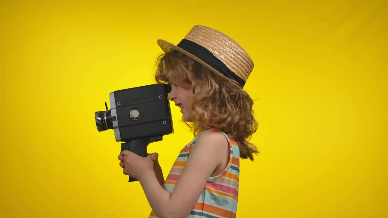 小女孩正在用复古摄像机拍摄黄色背景的视频视频下载