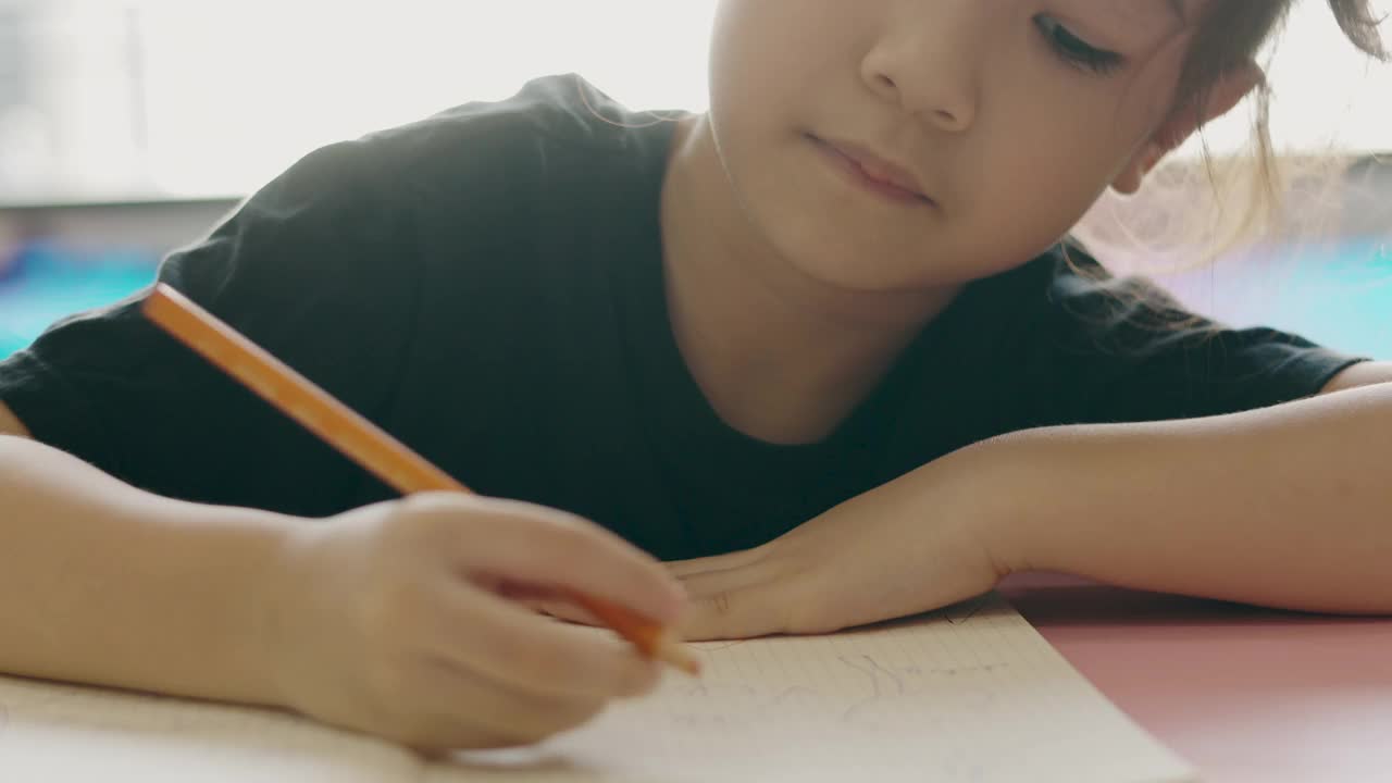 可爱的亚洲小女孩在阳光下的房间里写着她的纸质书，脸上的专注显示出孩子紧张和严肃的疲惫和无聊的感觉和课桌上的作业。视频素材
