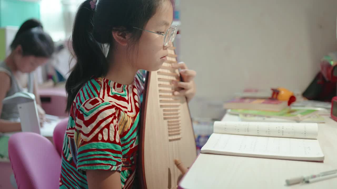 小女孩在弹琵琶(中国的琵琶，一种带有微动指板的拨弦乐器)视频下载