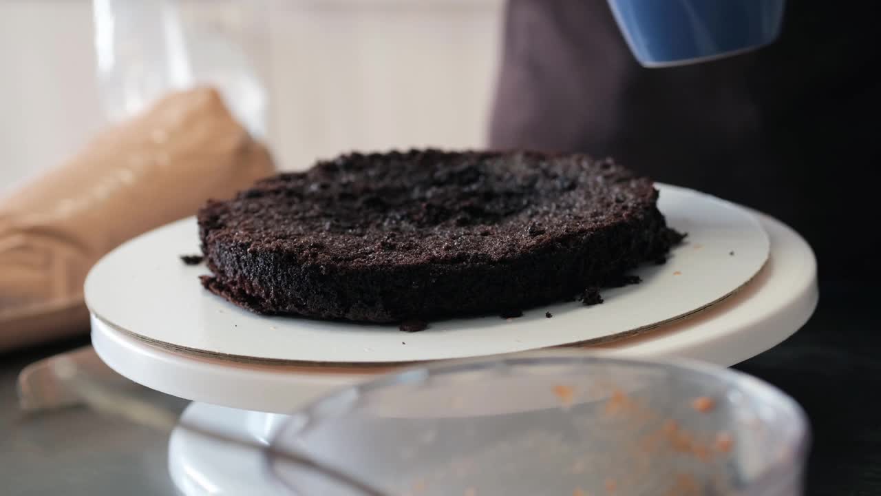 4K女糕点厨师在展台上让巧克力海绵蛋糕怀孕，特写镜头。缓慢的运动。蛋糕制作过程。视频素材