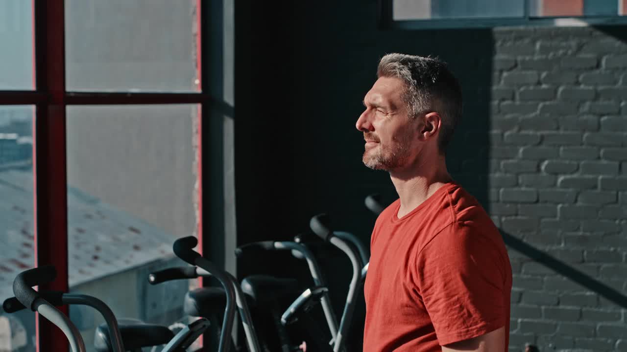 一个英俊成熟的男人在健身房锻炼后独自站着的4k视频片段视频素材
