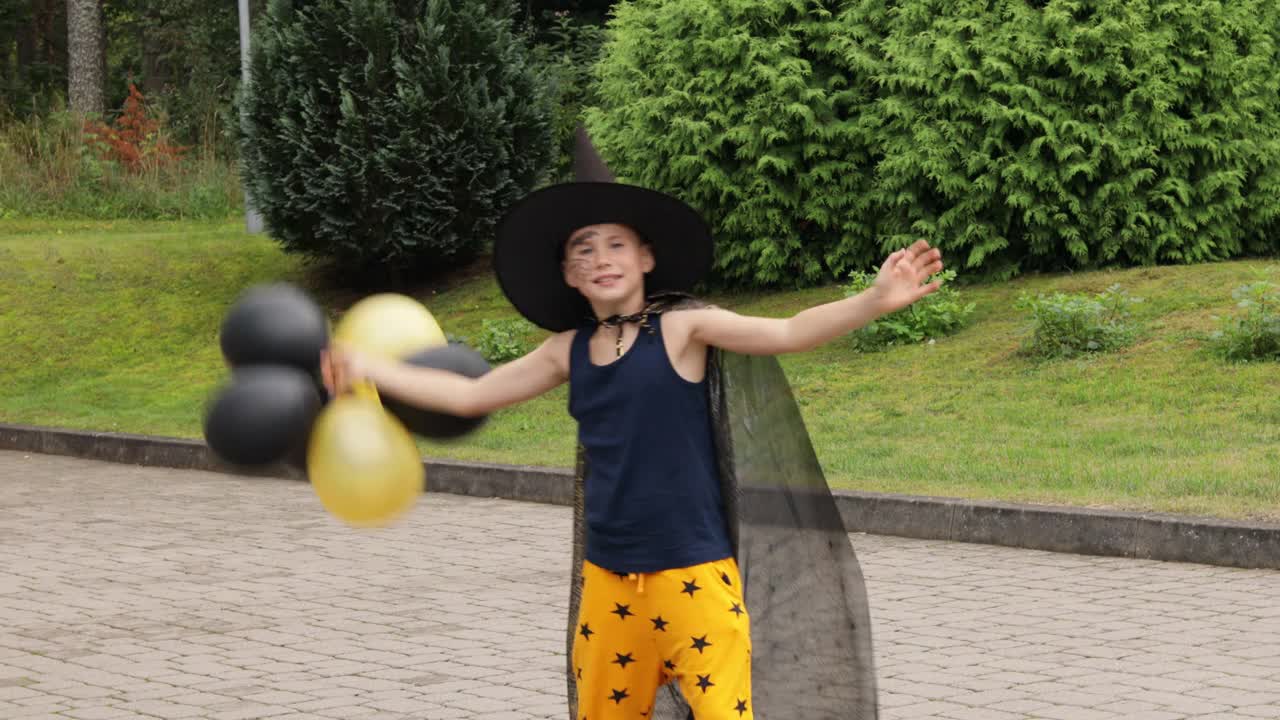 万圣节跳舞的男孩。穿着狂欢节服装的少年在户外。一名男生正在玩橙色和黑色的气球。视频素材