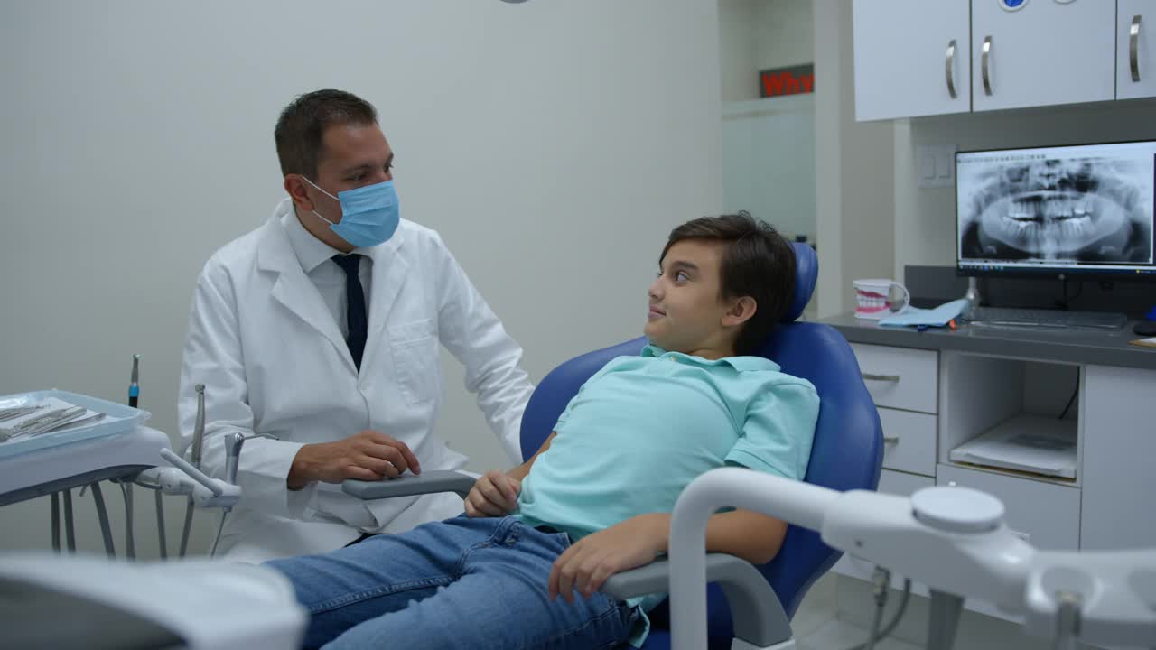 友好的正牙医生给一个十几岁的男孩击掌，因为他在会诊期间的表现视频下载