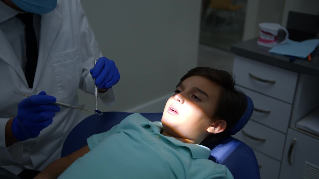 男孩张开嘴，男牙医检查他的牙齿视频素材