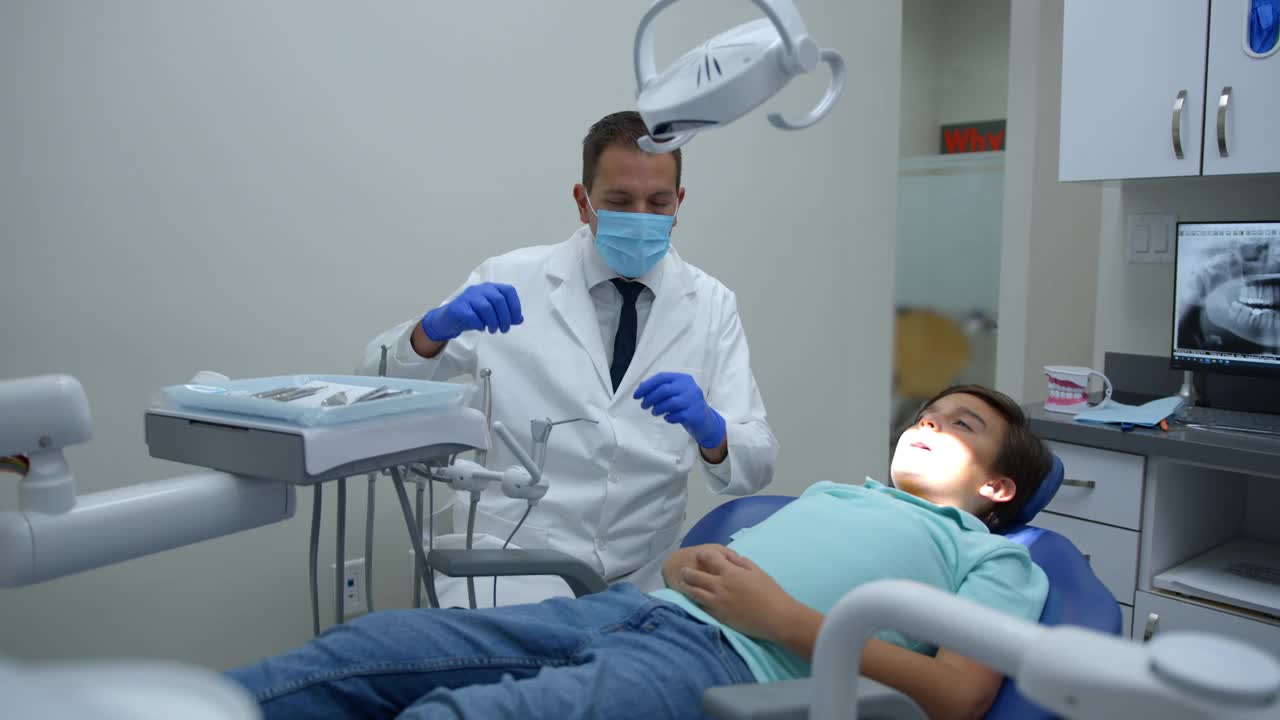 男牙齿矫正医生正在检查他的小病人的牙齿视频素材