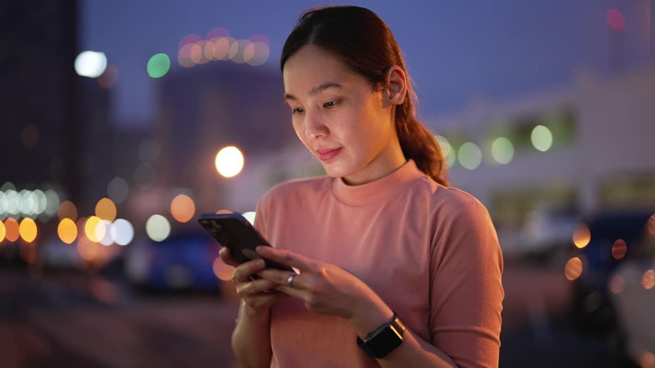 亚洲女人晚上在城市里用智能手机视频素材