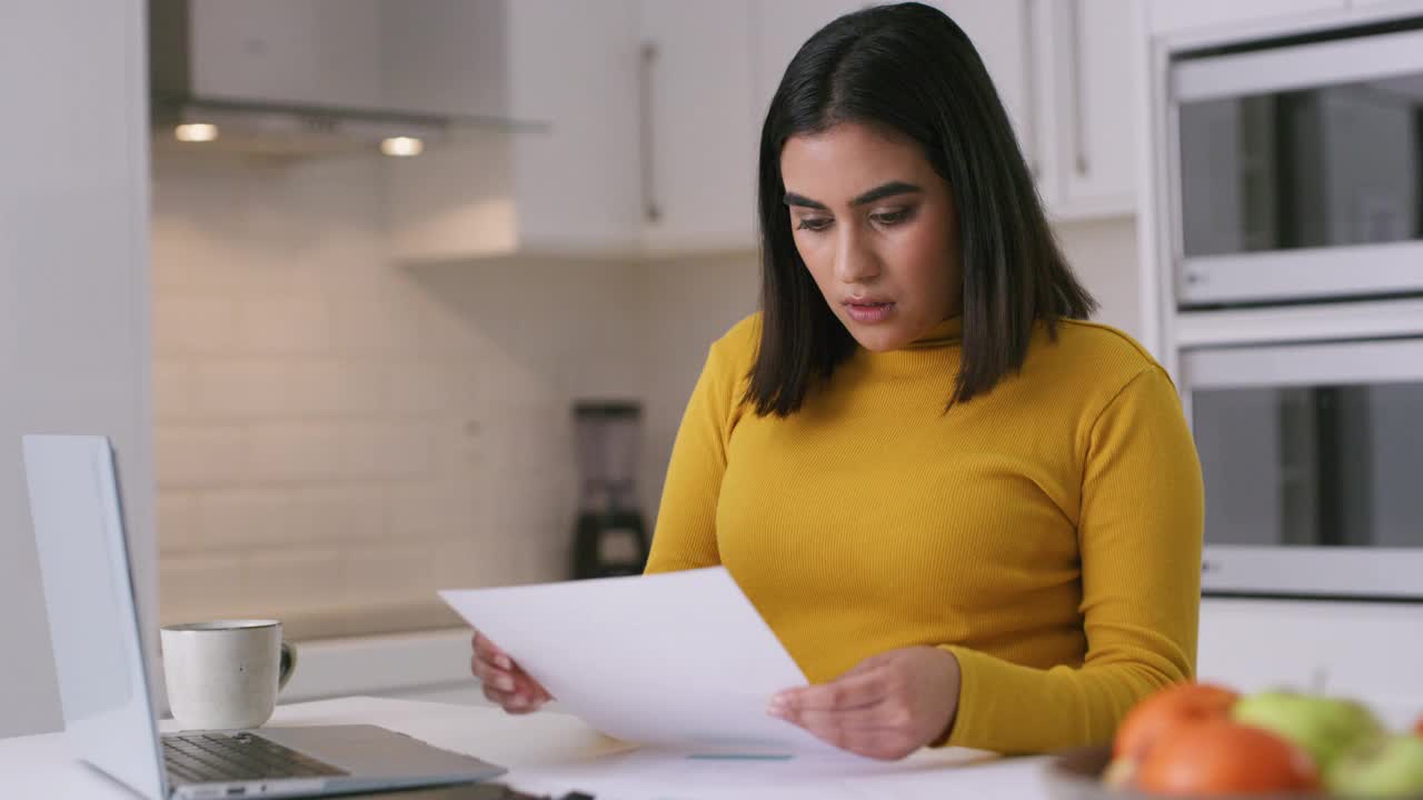 4k视频显示一位年轻女子在家里使用笔记本电脑和处理文书工作时看起来很紧张视频素材