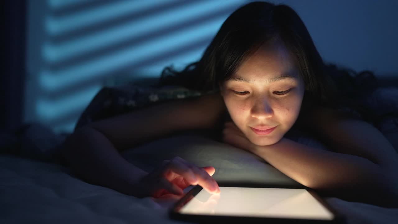 一名女子晚上在床上使用电子平板电脑视频素材