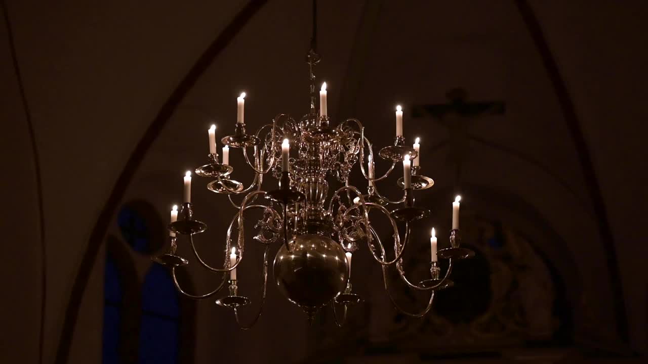 吊灯上有真正的燃烧和闪烁的蜡烛。在黑暗的背景下视频素材