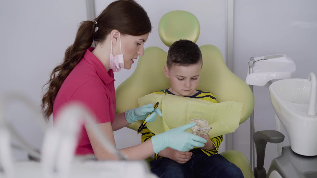 牙医向孩子展示如何使用牙刷和下颌布局来护理牙齿视频素材