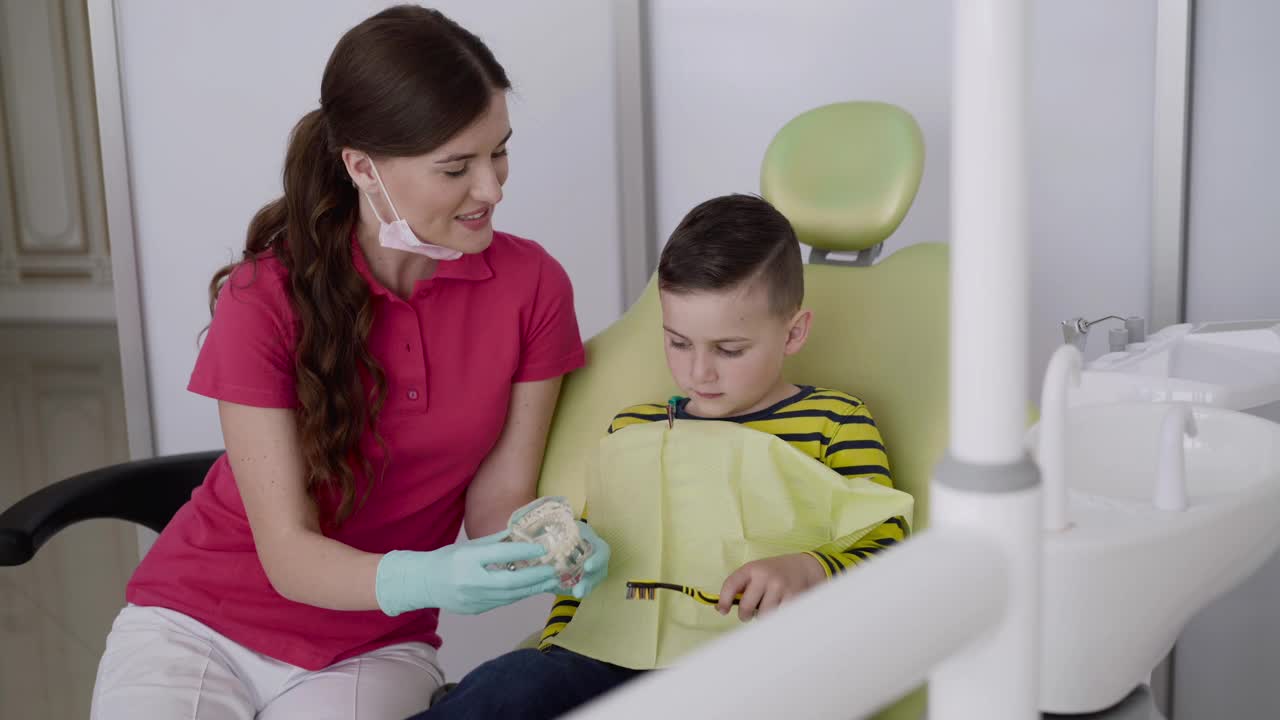 牙医向一个男孩展示如何正确使用牙刷和下颌布局刷牙视频素材
