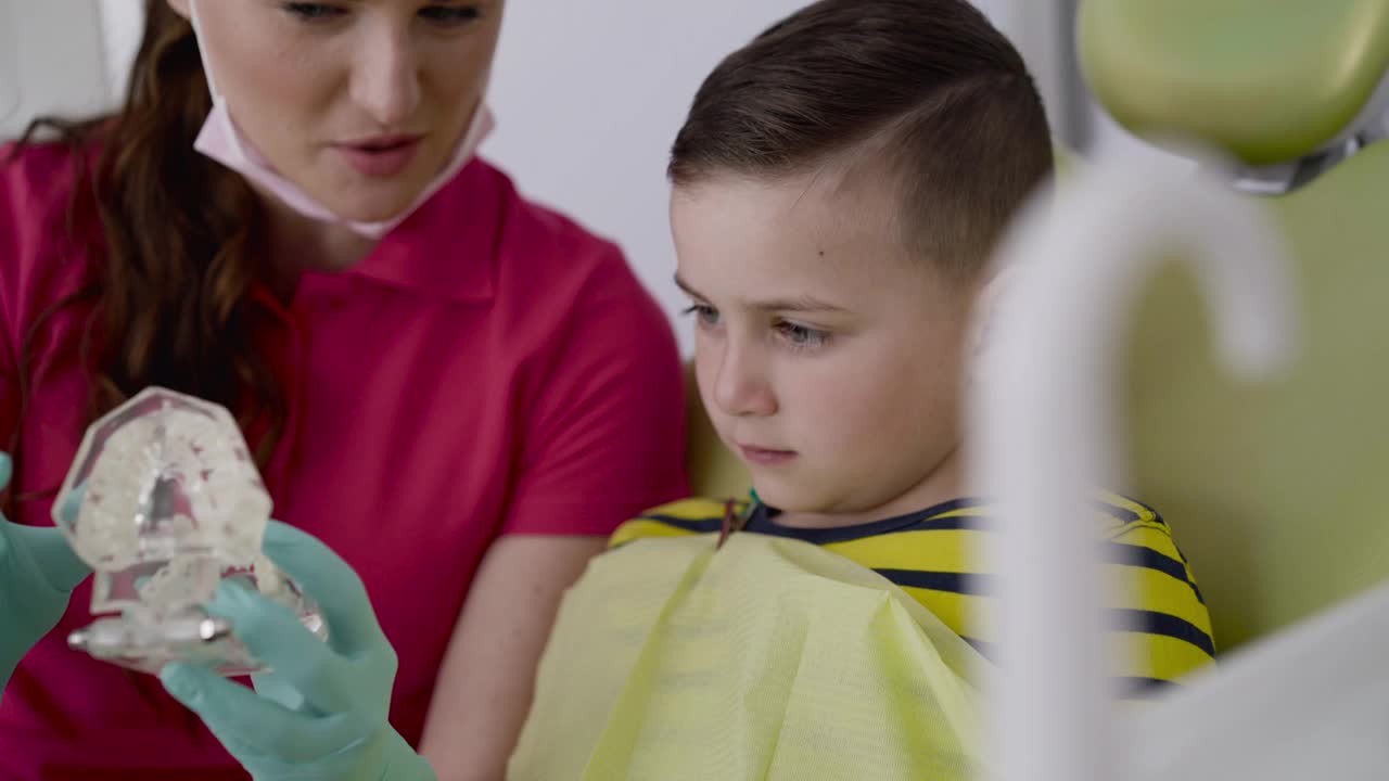 女牙医咨询了一个谦恭的男孩用下颌布局的细心口腔护理视频素材