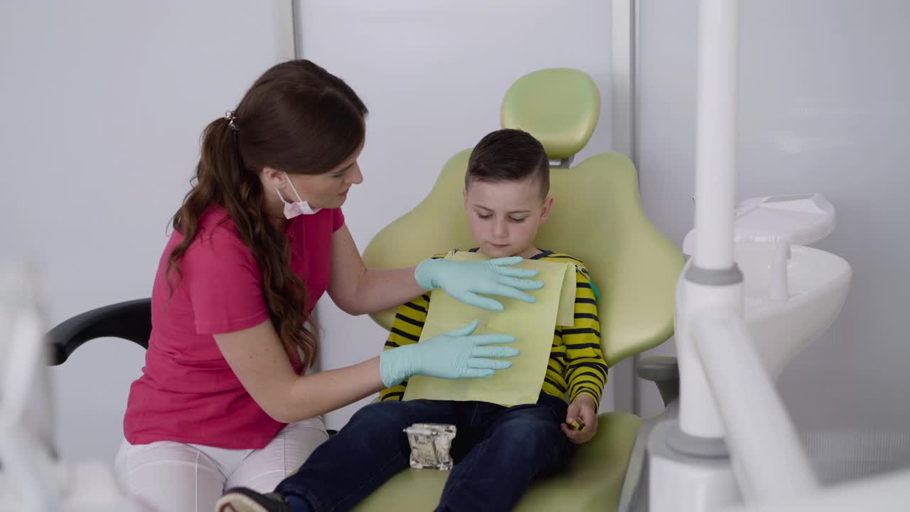 快乐牙医向男孩展示如何正确使用牙刷刷牙和下颌布局视频素材