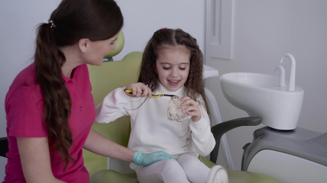 牙医向孩子展示如何使用牙刷和下颌模型刷牙视频素材