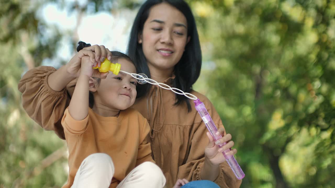 亚洲女孩和妈妈在公园玩泡泡视频素材