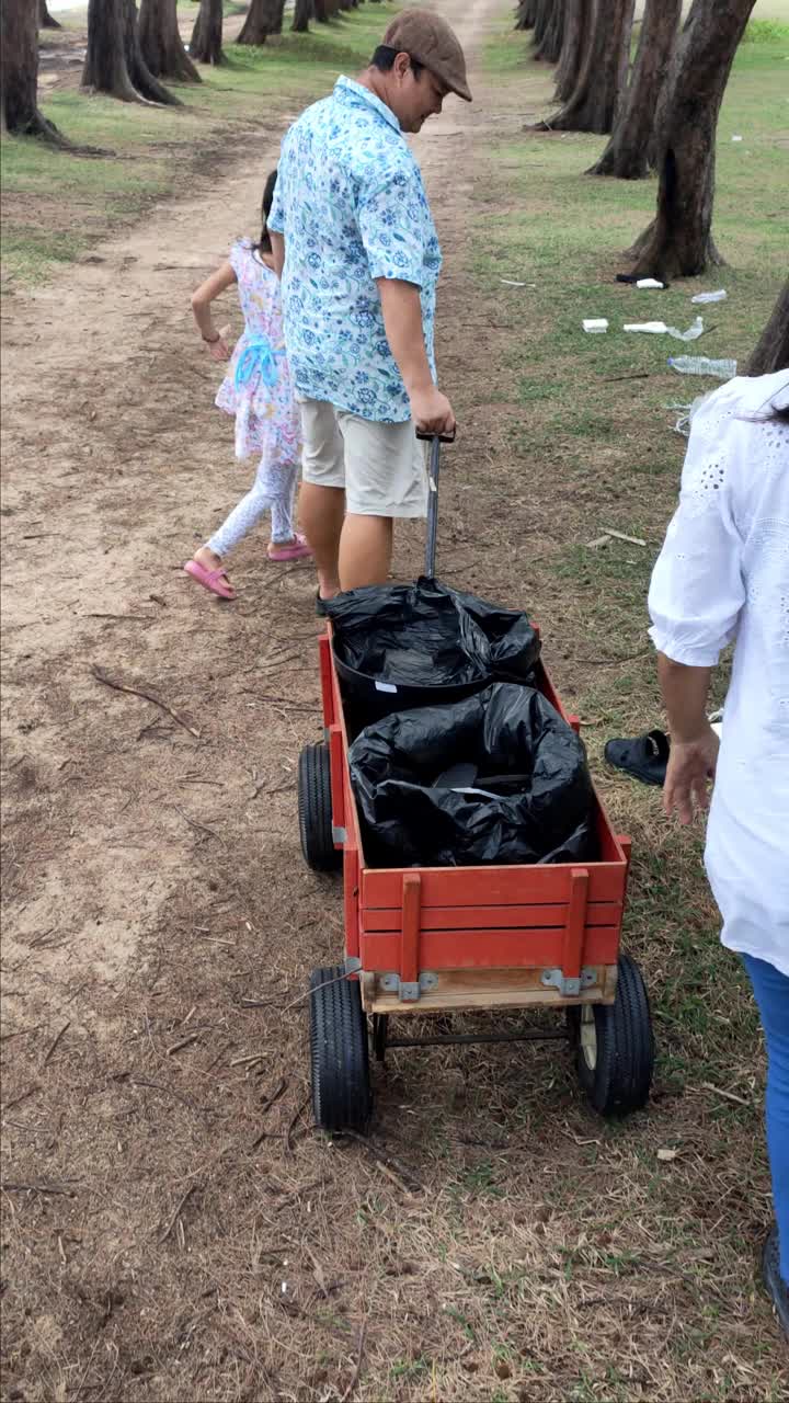 一个亚洲家庭用轮椅把垃圾放在海边公园里，以适当地限制垃圾。视频素材