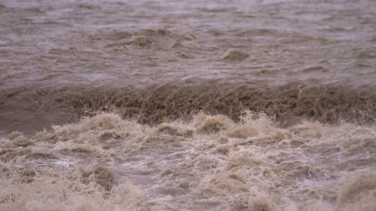 慢镜头-泥泞的河流溢出堤岸摄像机倾斜向下视频素材