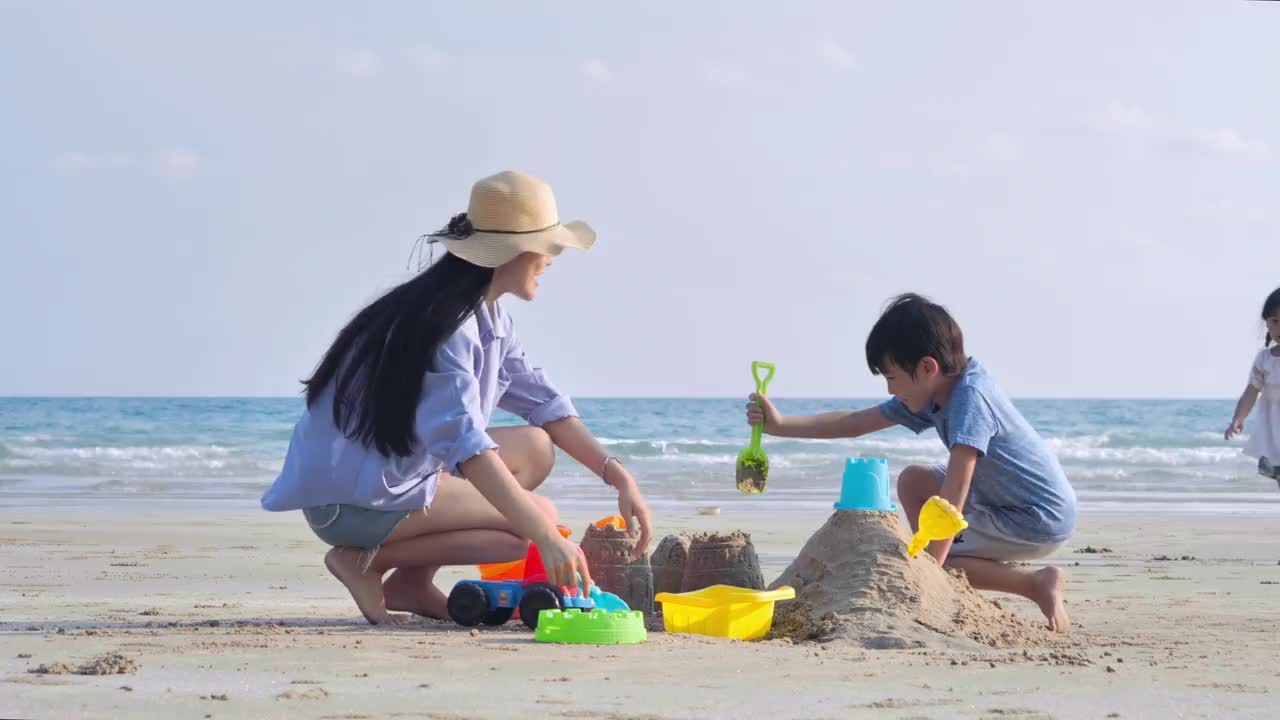 幸福的亚洲家庭的父亲，母亲与男孩和女孩4-8岁的沙子玩具在夏天的海滩上玩。活跃的父母和人们在热带暑假带着孩子进行户外活动。幸福的家庭假期。自然中的幸福理念。视频下载