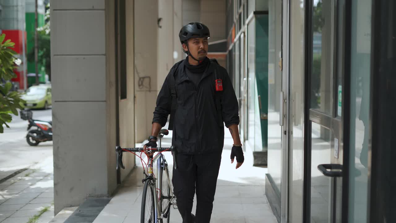 亚洲快递员走路，拖着自行车视频素材
