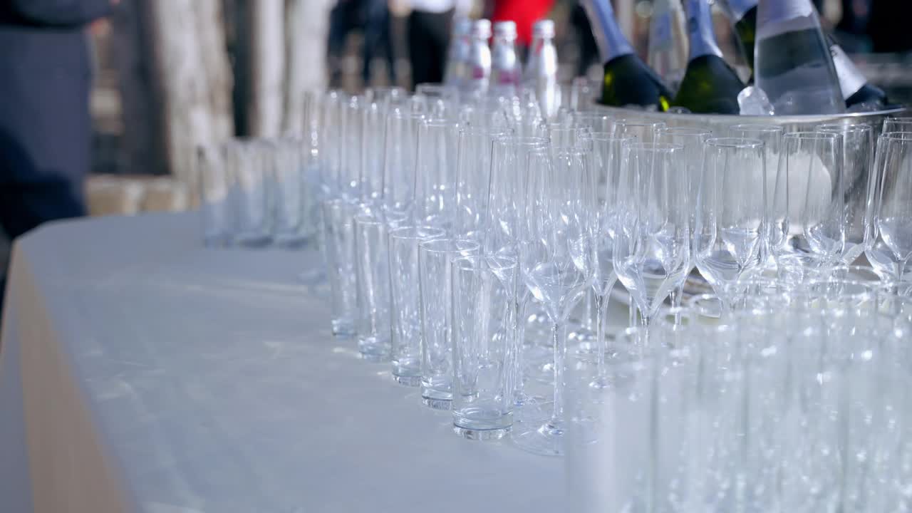 宴会桌上的一排水晶酒杯和香槟酒杯，旁边是装着酒瓶的银桶，是为庆祝宴会上的客人准备饮料的杯子。节日庆典用的葡萄酒和香槟酒杯视频素材