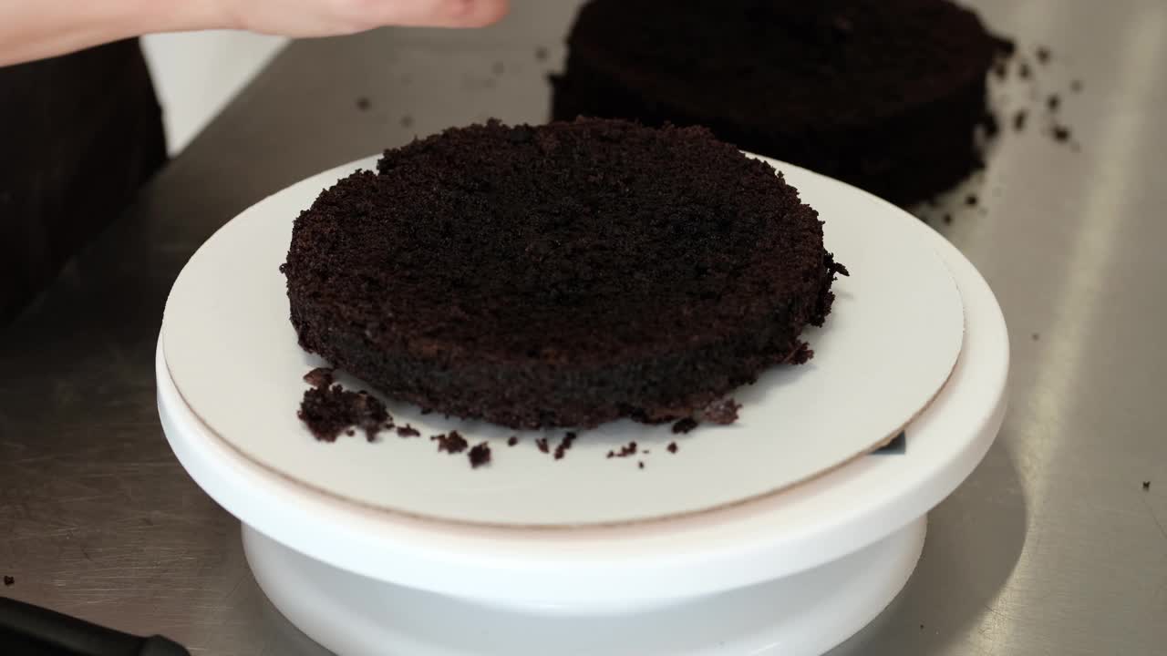 4K女糕点厨师将巧克力海绵蛋糕摆放在制作和装饰蛋糕的架子上，特写镜头。缓慢的运动。蛋糕制作过程。视频素材