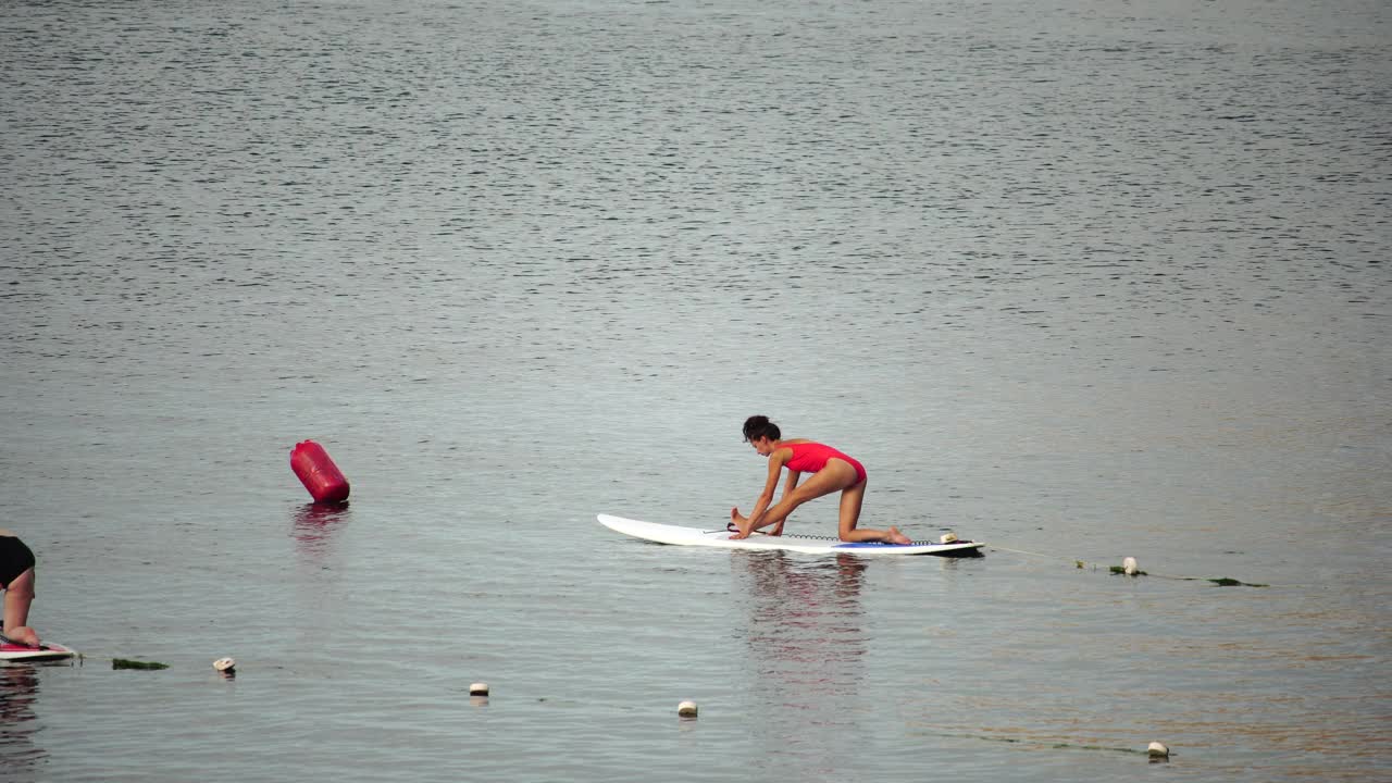 清晨，一群身着泳装的年轻女子在平静的海面上做瑜伽。平衡姿势-健康生活和身心发展之间的自然平衡的概念视频素材