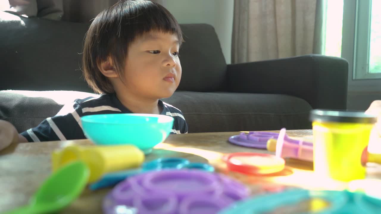母亲和儿子在家里的客厅里一起玩玩具和玩面团视频下载