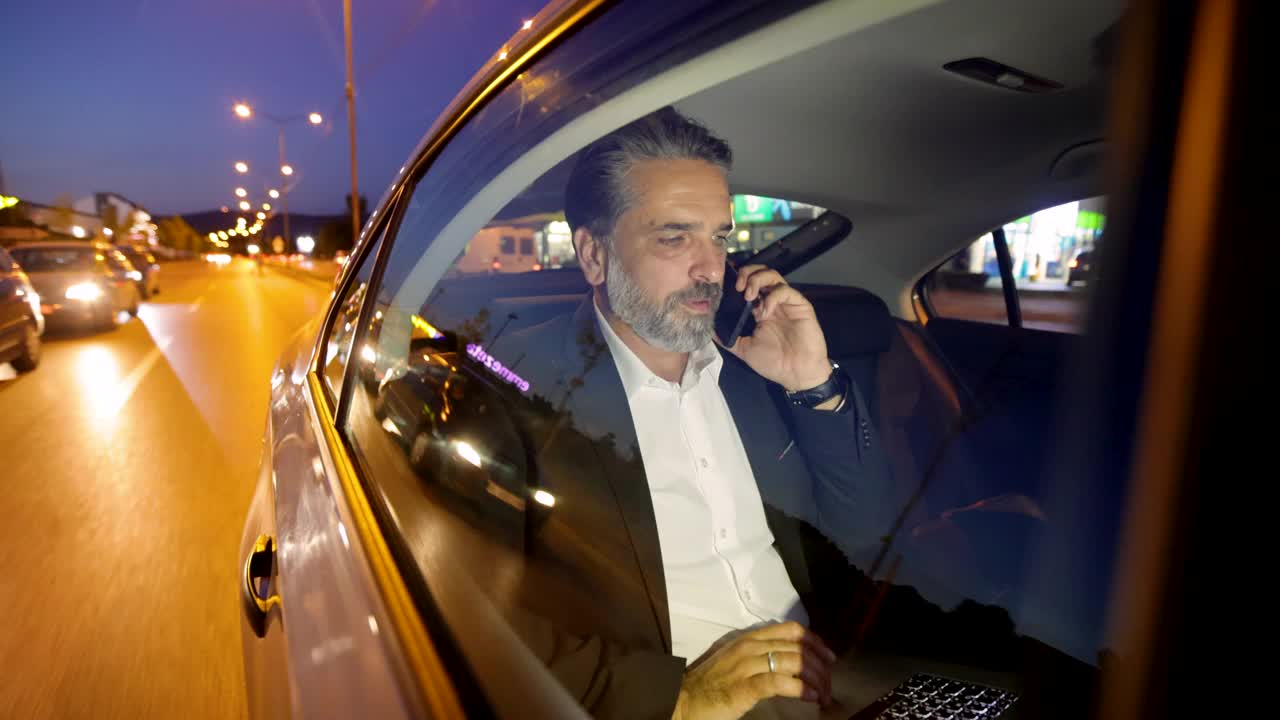 一个灰白头发和胡子的现代成熟男人在汽车里通过电话交谈视频素材
