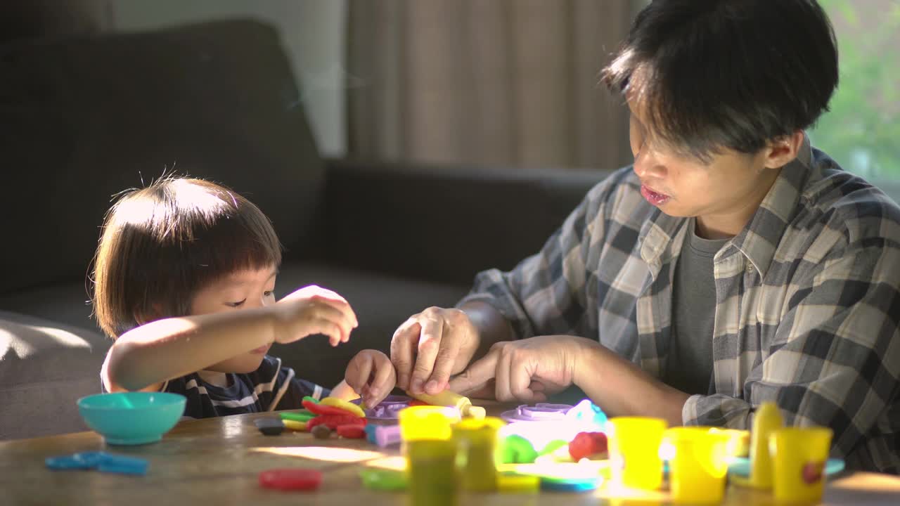 父亲和儿子在家里的客厅里一起玩玩具和玩面团视频下载