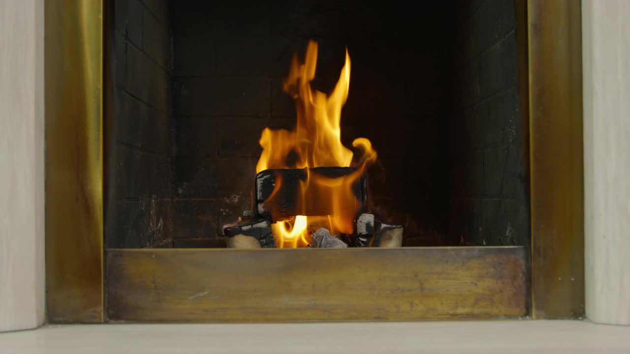在舒适的壁炉氛围中，靠近燃烧着橙色火焰的木头。用火砖在石头壁炉里燃烧木柴视频素材