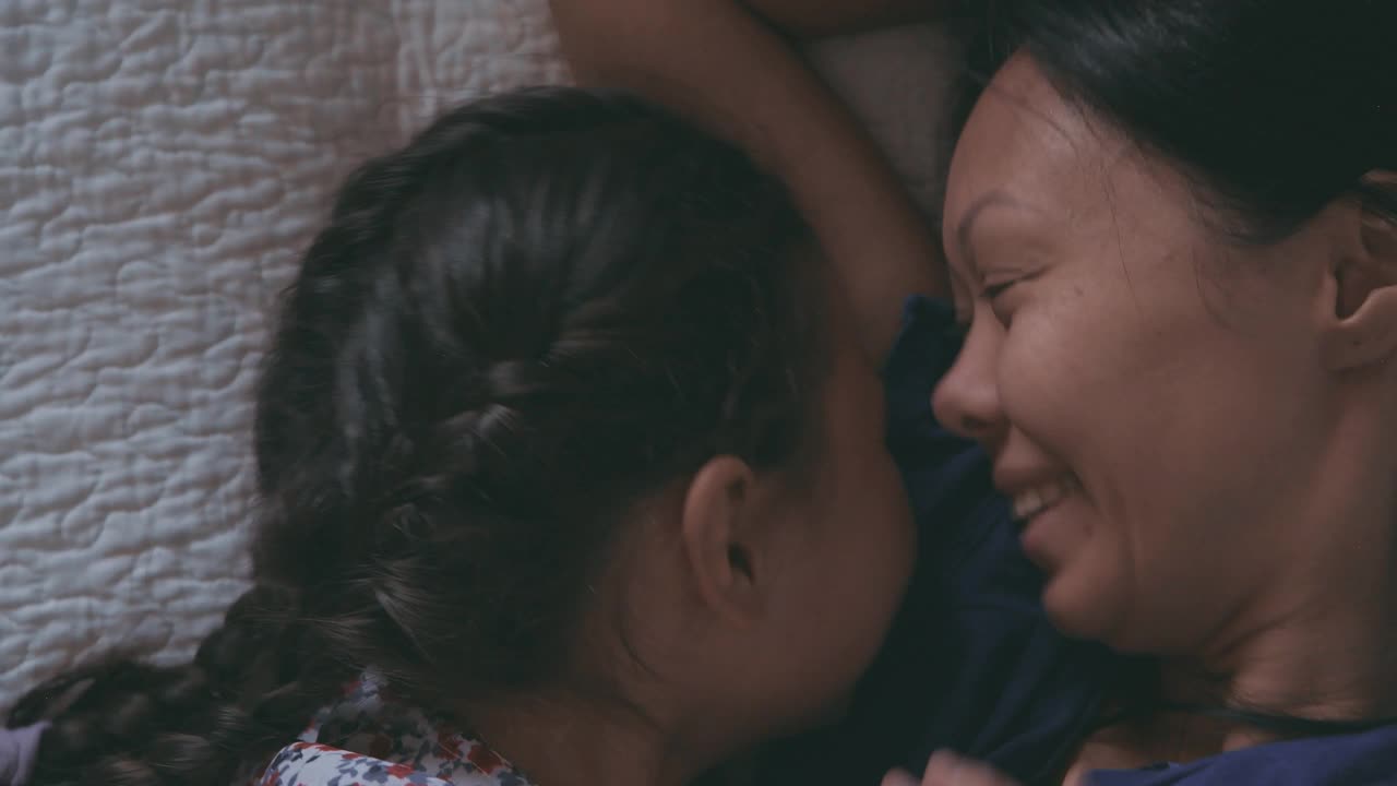 妈妈和女儿躺在床上，开心地拥抱着视频素材