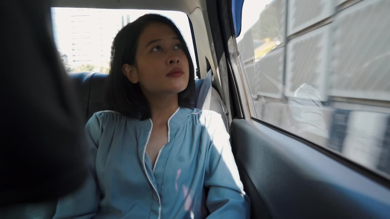 一个亚洲女人坐在汽车后座上视频素材
