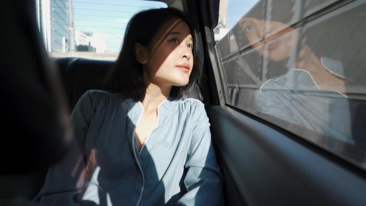 一个亚洲女人坐在汽车后座上视频素材