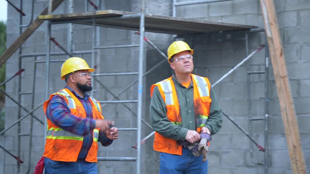 两名建筑工人在工地边走边聊视频下载