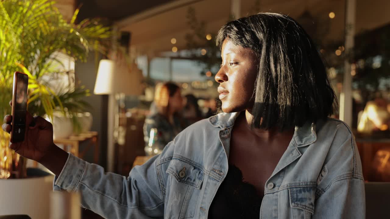 一个微笑的女人用手机视频通话，在咖啡馆里度过一段宁静的时光视频素材