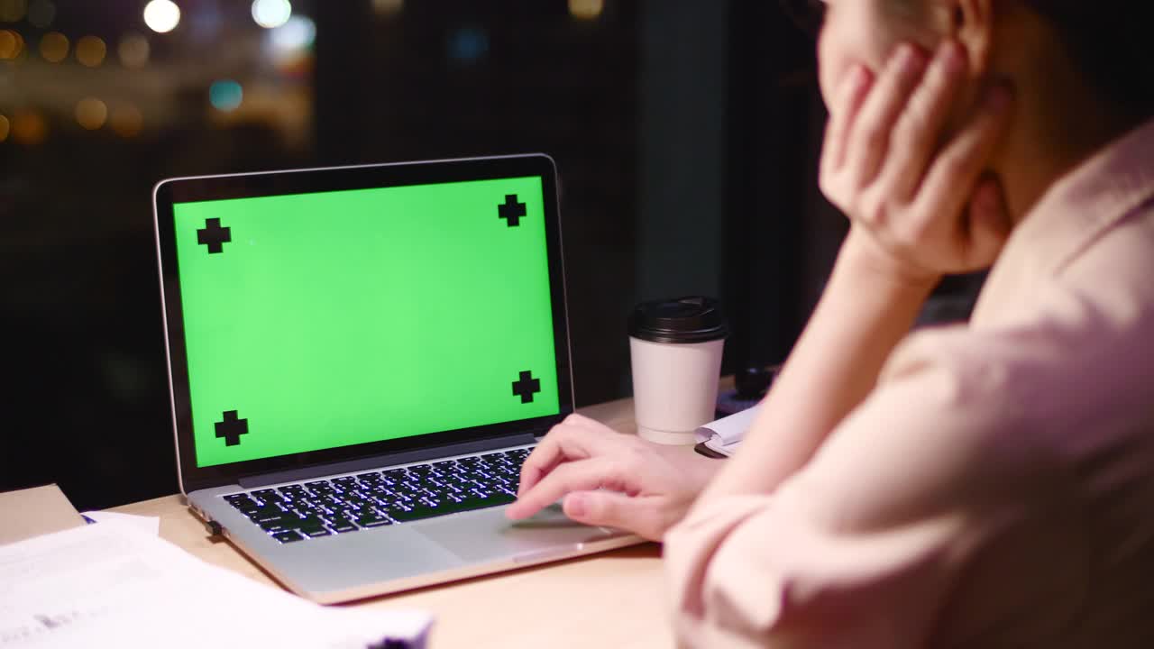 女人在晚上使用绿色屏幕的笔记本电脑视频下载