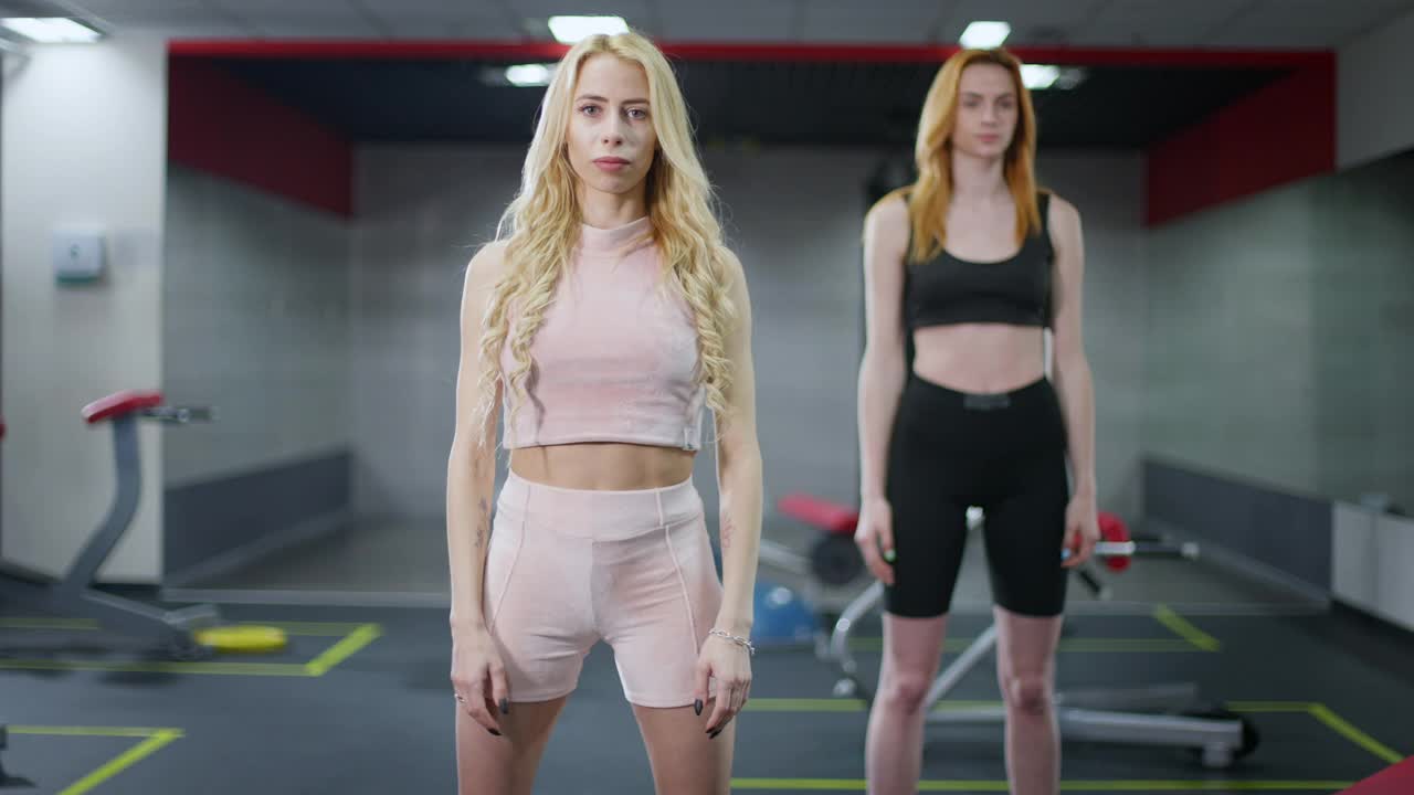 专业积极的健身教练的肖像，一边看着摄像机一边热身手部肌肉。苗条美丽的白人女性在室内健身房里训练。锻炼视频素材