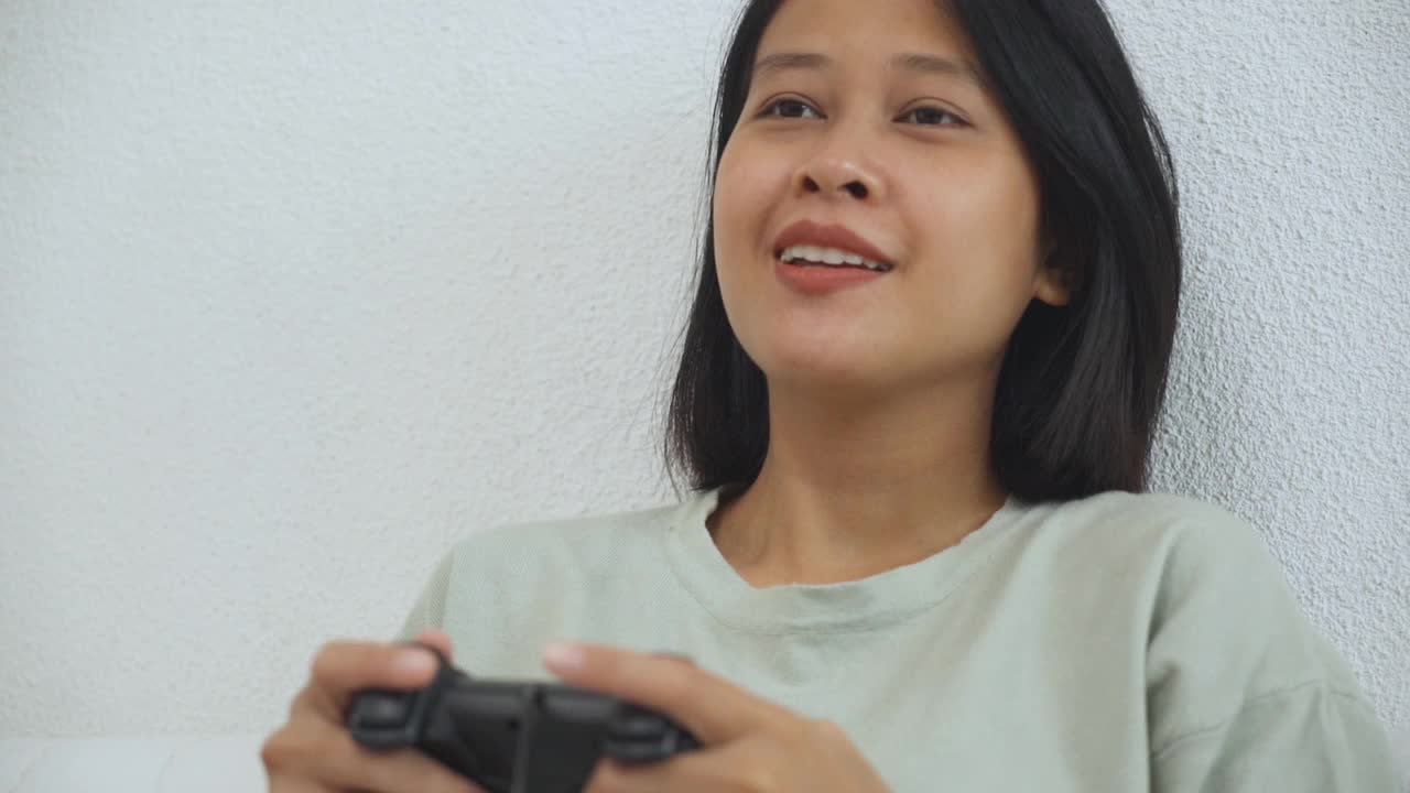 亚洲年轻女子用摇杆在客厅玩电子游戏的慢动作视频下载