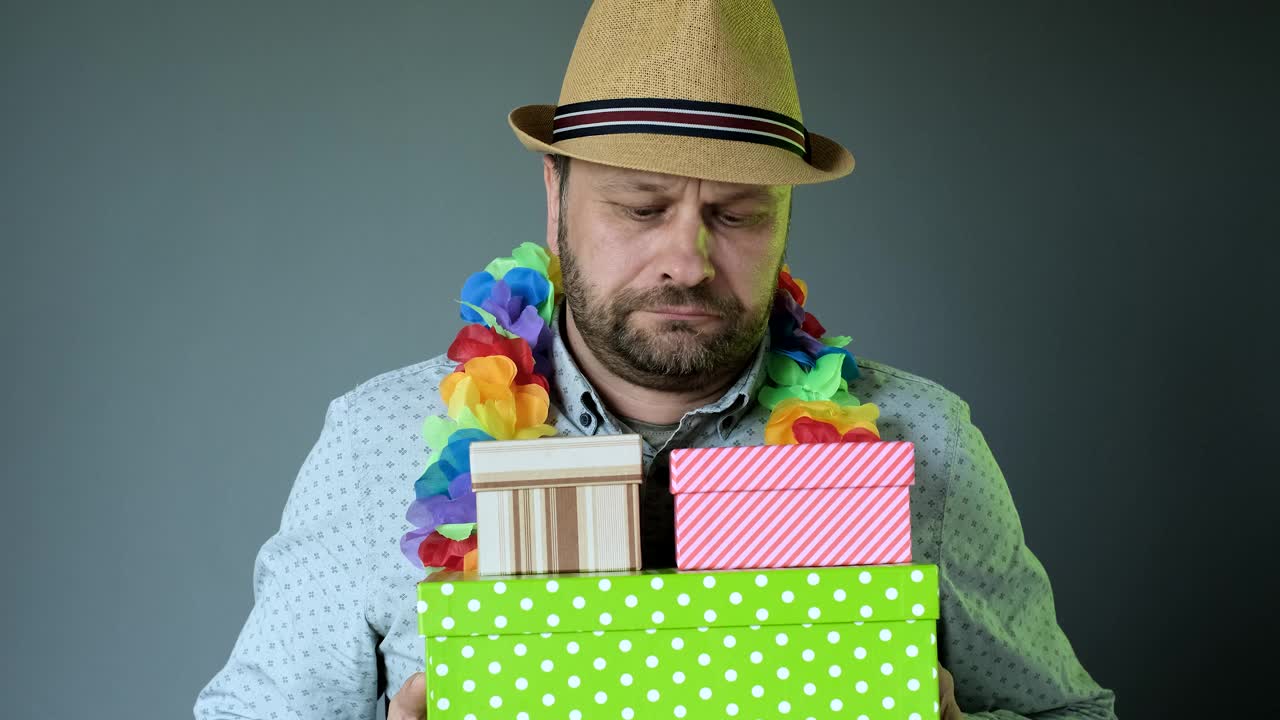 不开心的中年男人戴着帽子，感到焦虑抑郁，沮丧沮丧的礼物盒。
看着礼品盒和相机。心理问题的概念。肖像视频下载